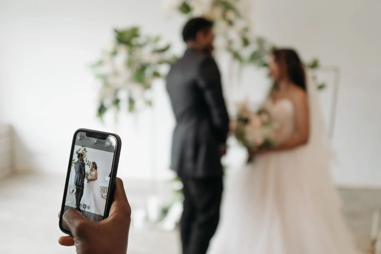 Gast maakt met haar telefoon een foto van het bruidspaar